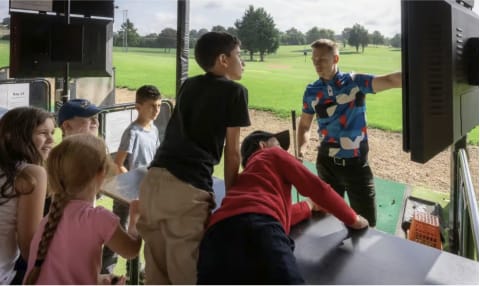 A group of junior golfers having a lesson on the driving range in dartford