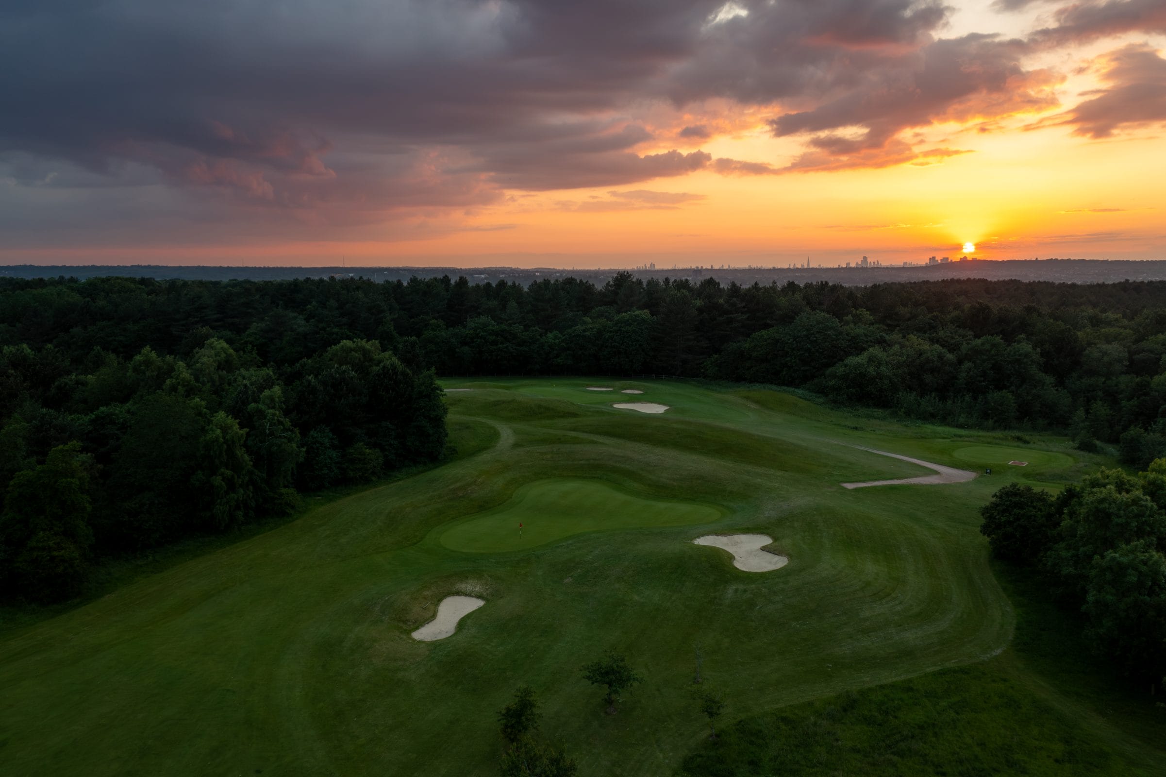 Drone footage of the golf course at sunset with bunkers