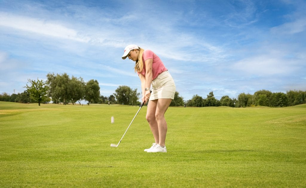 female golfer hitting the ball towards camera at birchwood park