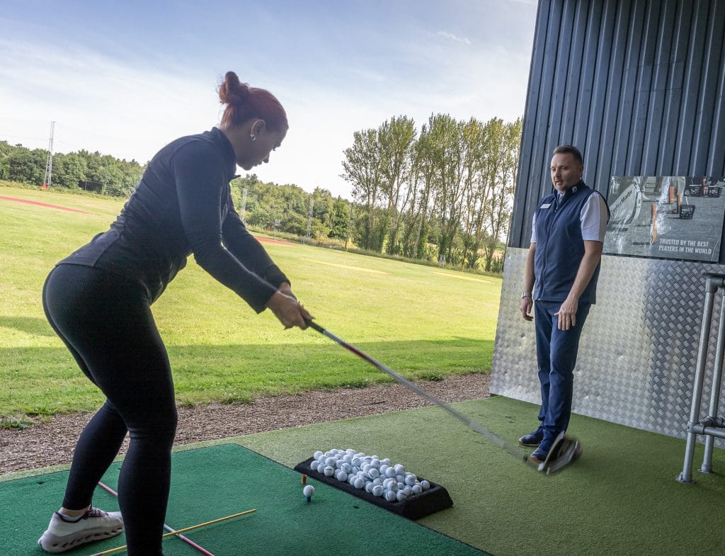 Person having a lesson on the driving range in kent about to hit balls