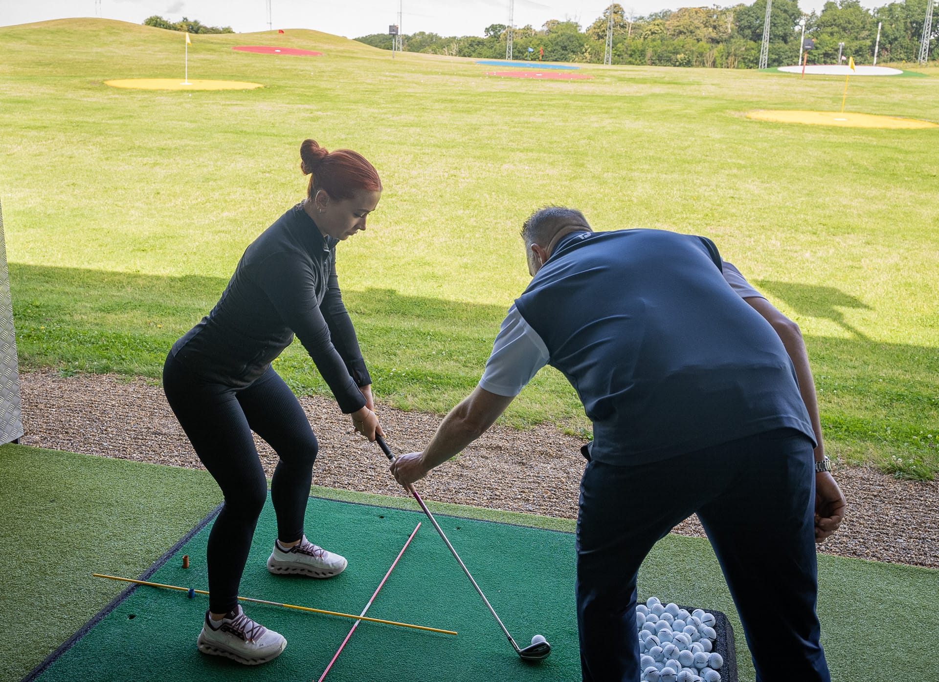Woman having a golf lesson on the driving range with the coach in kent