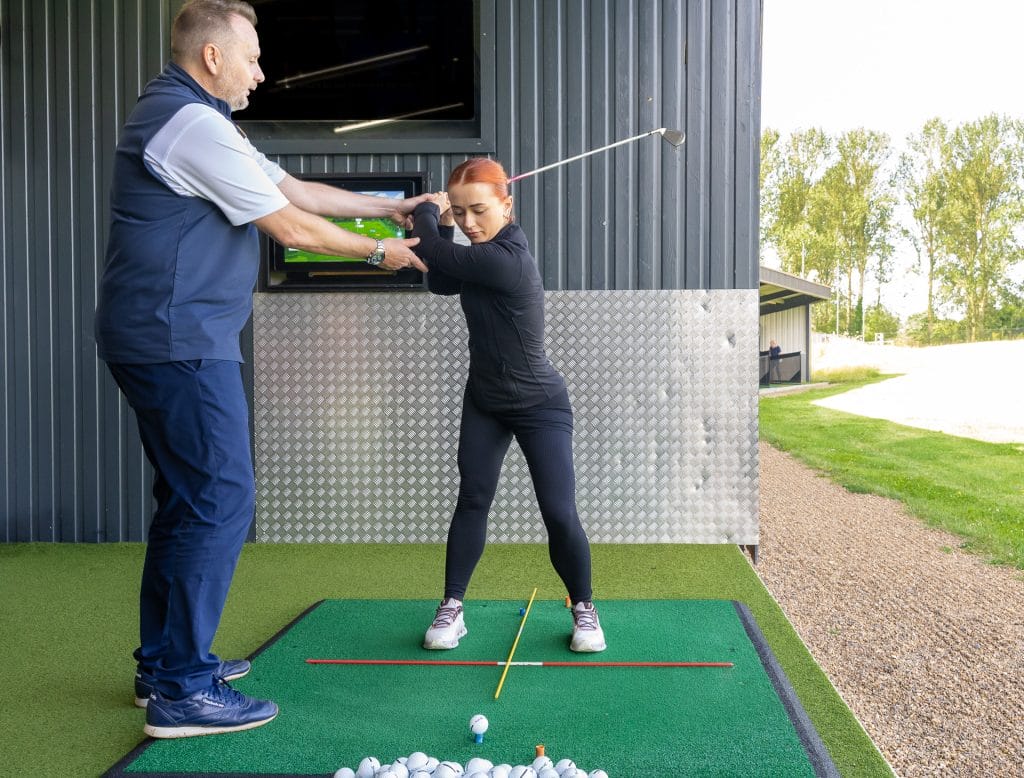 golfer in backswing getting a lesson in kent by a proffesional