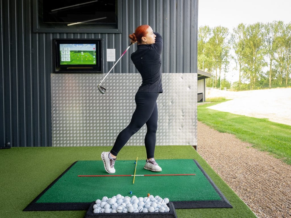 golfer hitting ball during golf lesson in dartford
