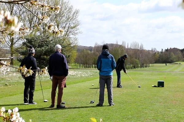 Group of golfers in the winter playing golf, with one about to tee off