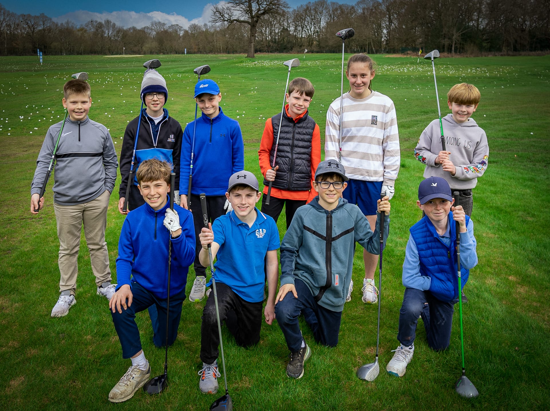 Group of junior golfers holding golf clubs at a junior lesson