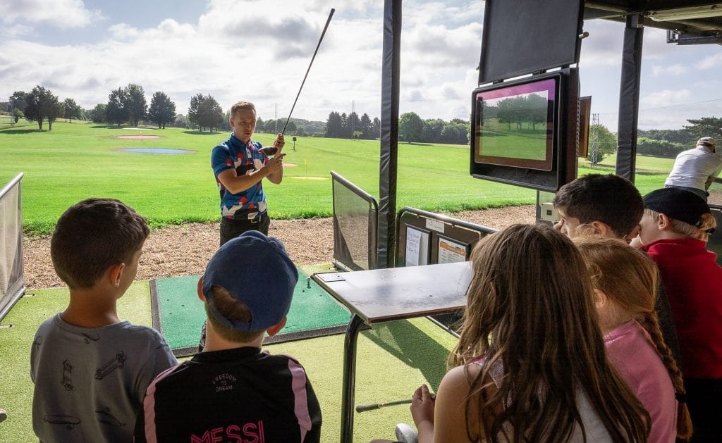 Group of junior golfers having a lesson on the driving range