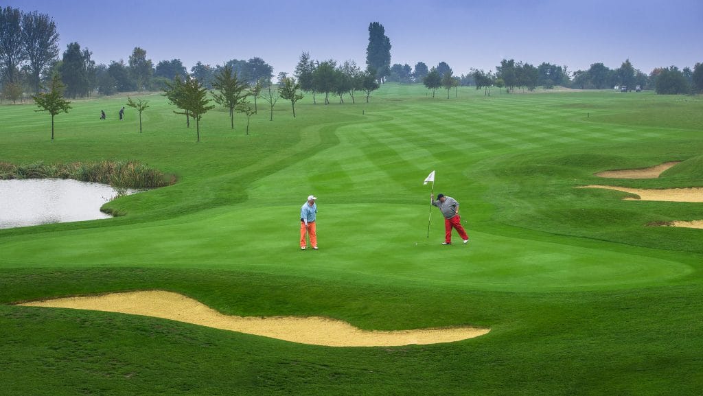 two golfers putting on neatly cut green i n dartford