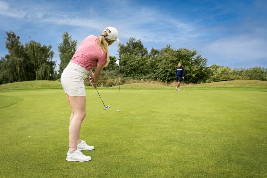 Woman taking golf shot on green
