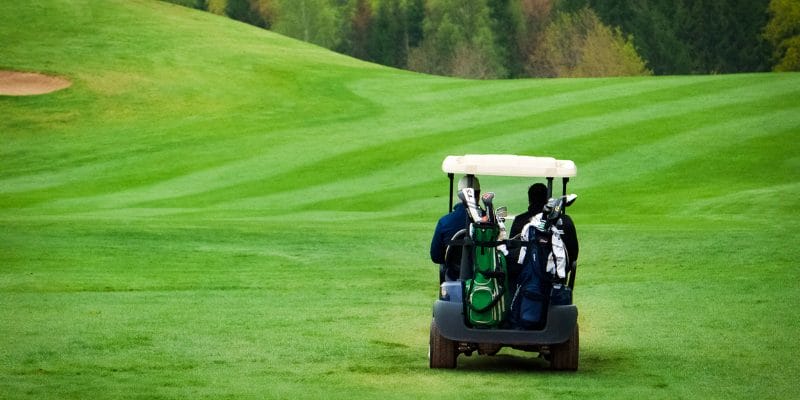 Buggy on green 18 hole golf course in kent with two people sitting in it